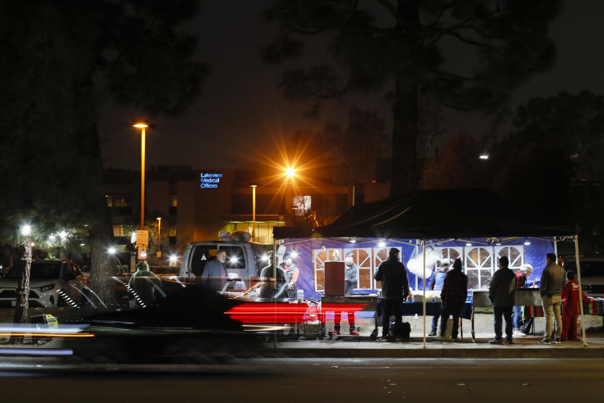 Customers line up in front of a food stand at night in Anaheim.