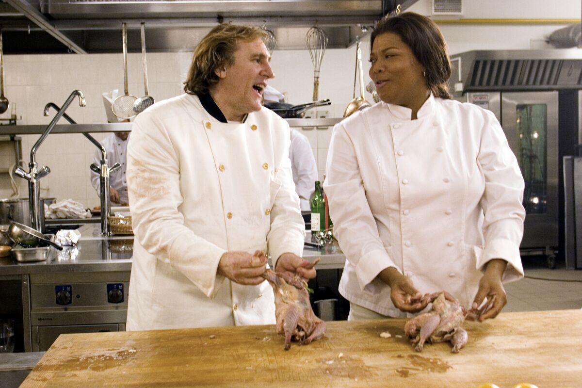 a man and a woman wearing chef garb prepare chicken in a scene from the movie ”last holiday.
