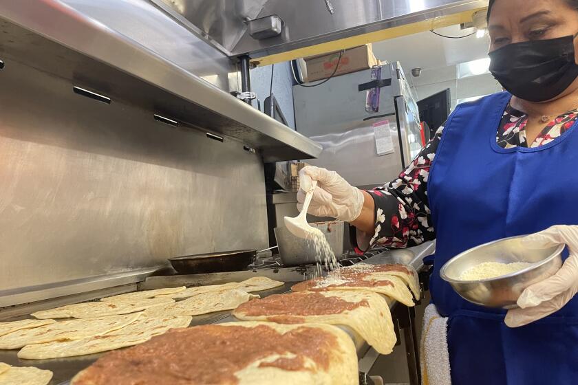 Blanca Pérez, propietaria del restaurante Rincón Hondureño, coloca frijoles, queso y crema a unas baleadas tradicionales.