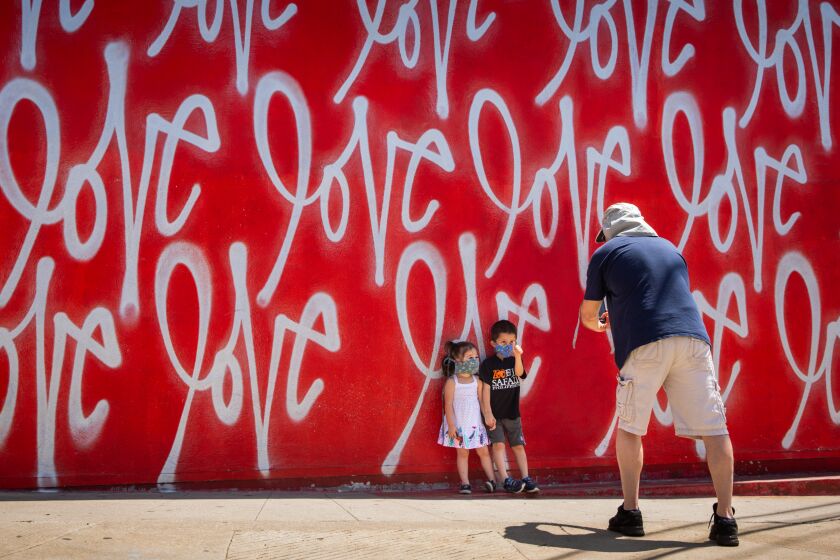 CULVER CITY, CA - APRIL 27: Tom Sean Foley pauses on a walk with his kids, Cathelen Claire, "C.C.," 3 and Timothy Joseph,4, to take a photo in front of the "Love Wall," mural by artist Curtis Kulig, outside of Smashbox Studios in Culver City, CA, during the coronavirus pandemic, Monday, April 27, 2020. (Jay L. Clendenin / Los Angeles Times)
