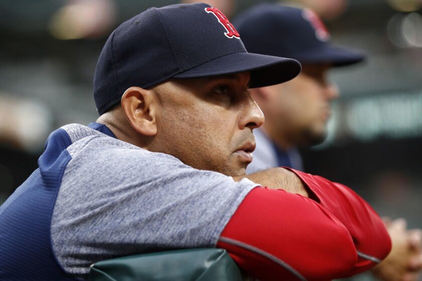 FILE - In this July 24, 2018, file photo, Boston Red Sox manager Alex Cora leans against the dugout rail during the second inning of the team's baseball game against the Baltimore Orioles in Baltimore. The Red Sox rewarded Cora for winning a World Series in his first year with the team, giving him a new contract that includes an additional guaranteed year through the 2021 season, in a deal announced Wednesday, Nov. 14. (AP Photo/Patrick Semansky, File)