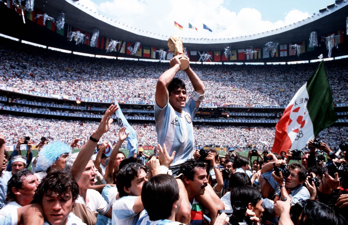 Argentina captain Diego Maradona holds the World Cup trophy while being carried on his teammates' shoulders.