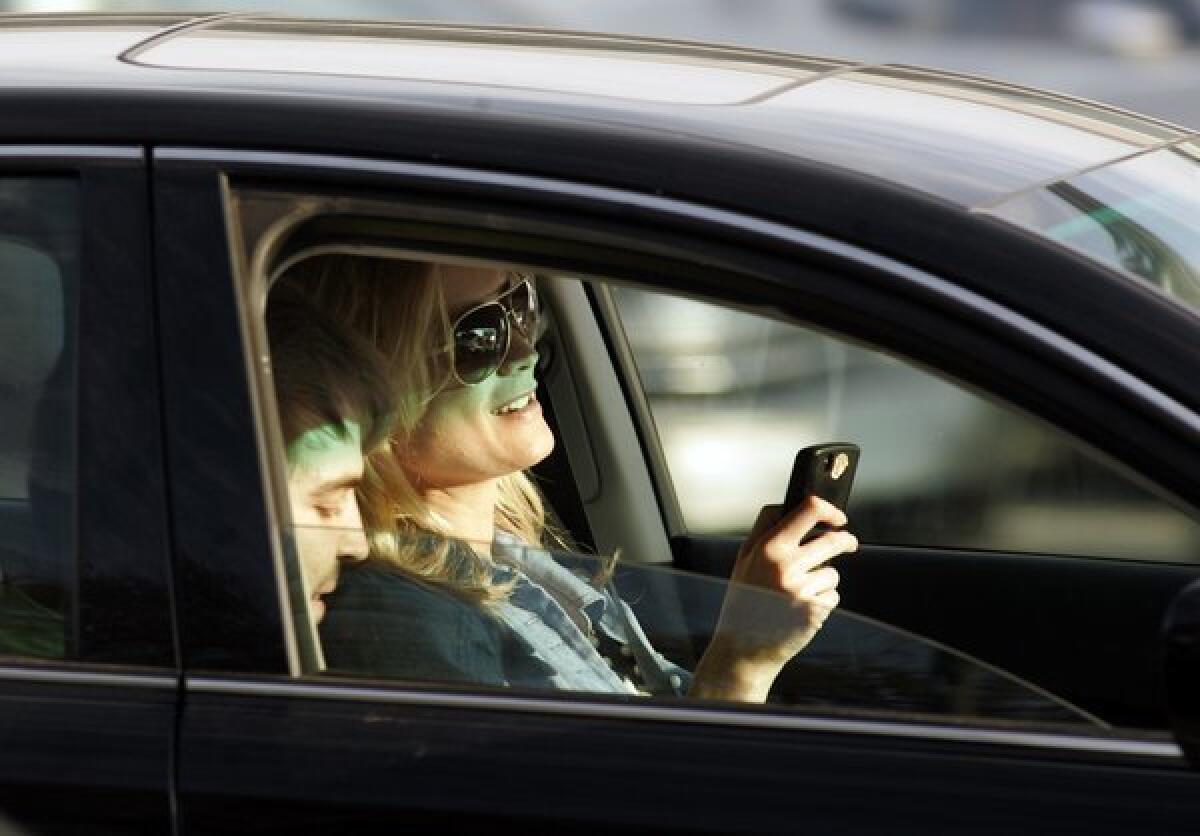 A motorist appears to be texting while driving through the intersection of Santa Monica and Wilshire boulevards in Beverly Hills.