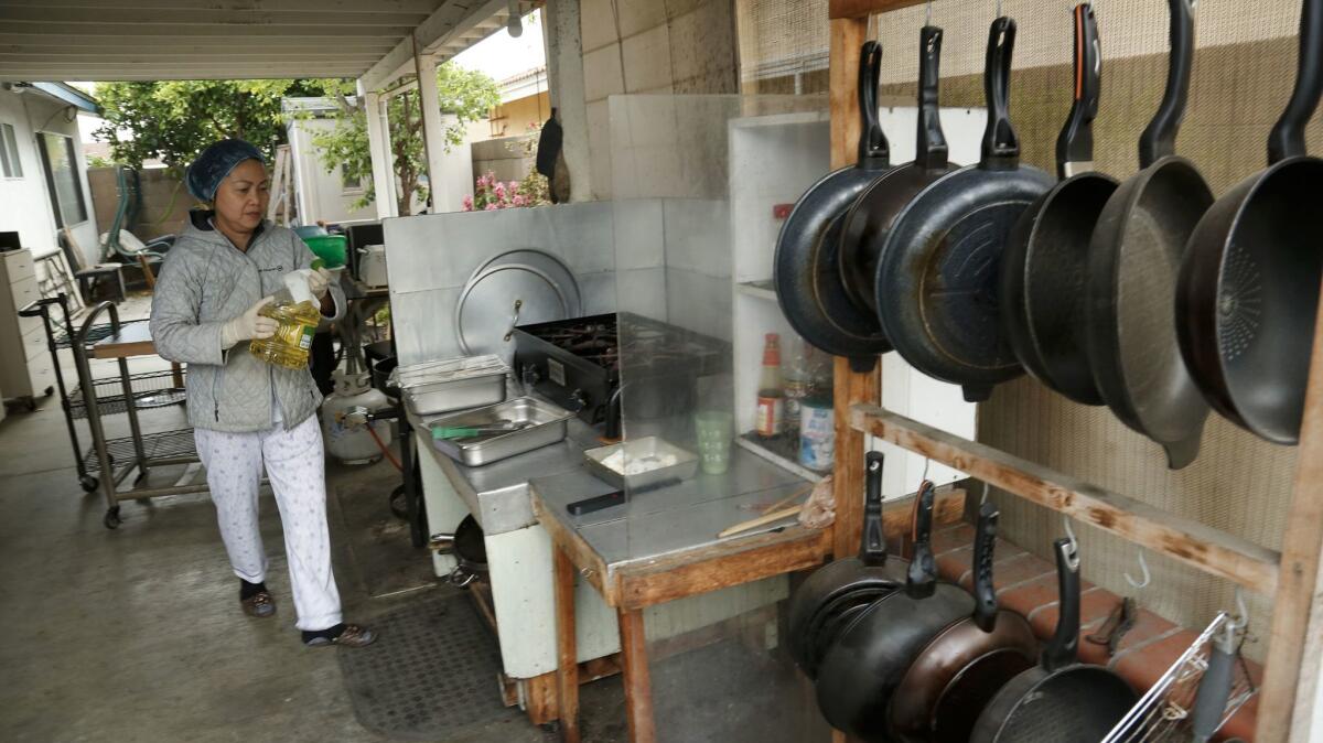 Pots and pans are neatly organized while Hue Phan plans menus in her patio kitchen.