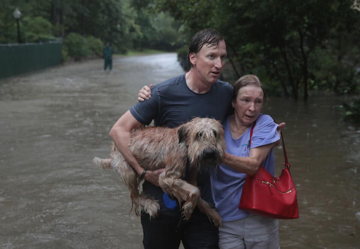 Andrew White helps a neighbor after rescuing her from her home in his boat in Houston's River Oaks neighborhood on Sunday. (Scott Olson / Getty Images)