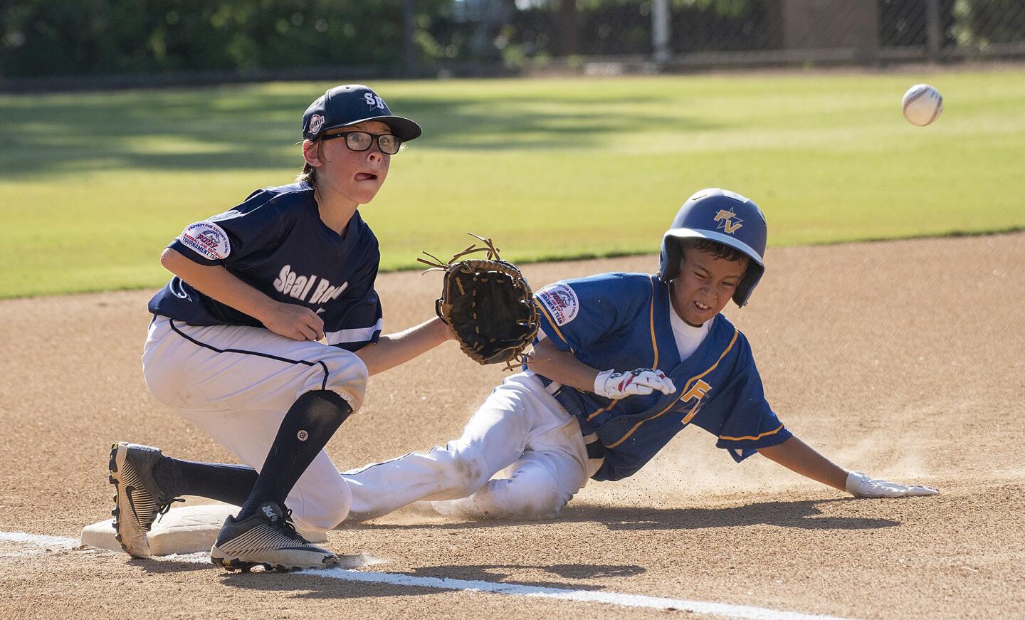 Fountain Valley's Andrew Castillo beats the throw at third against Seal Beach's Ryder Velasco-Buonassissi during a PONY Mustang 11-and-under Regional tournament at Hicks Canyon Park in Irvine on Thursday, July 12.
