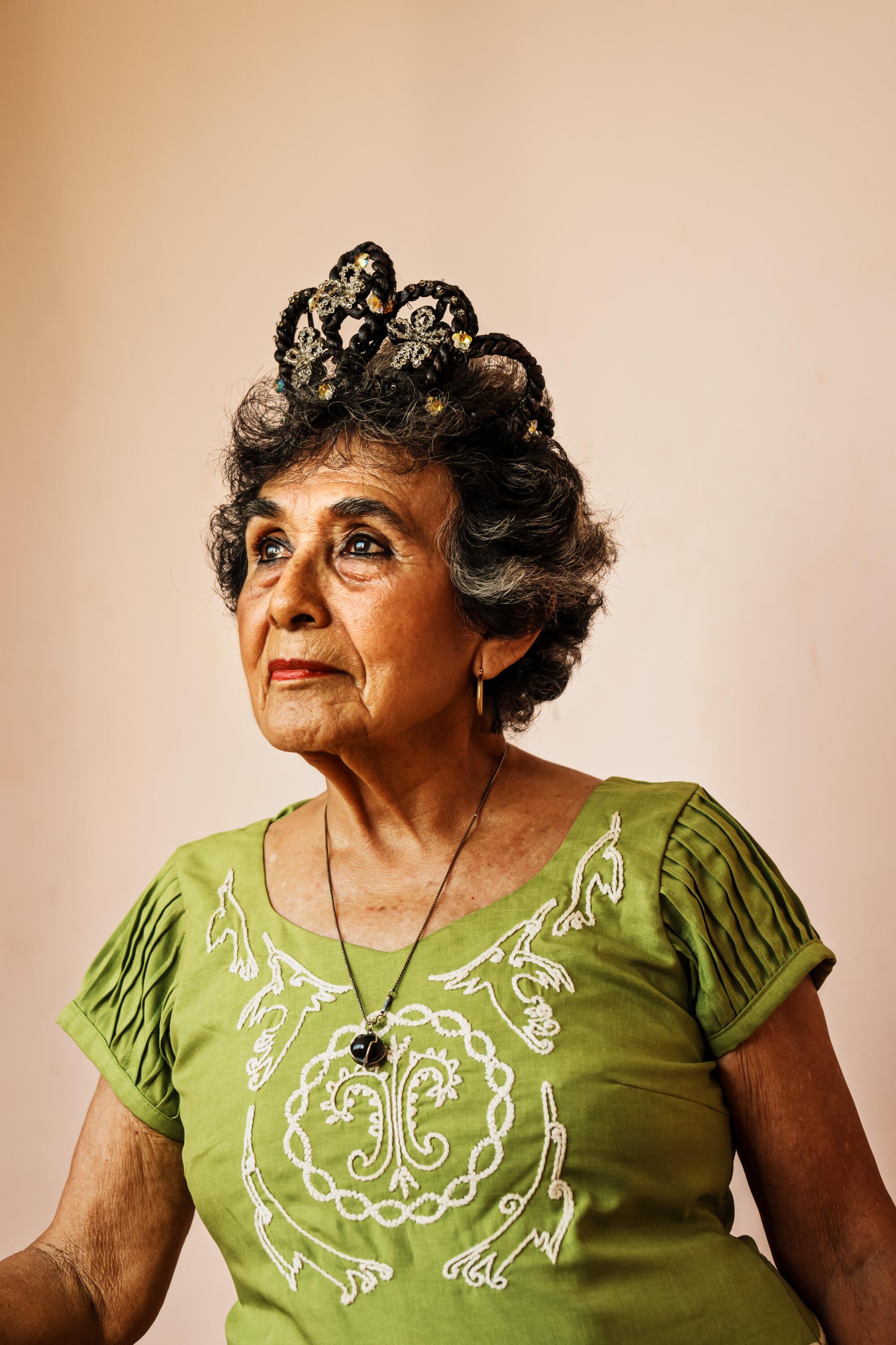 84 岁的阿尔玛·罗莎·冈萨雷斯·埃雷拉 (Alma Rosa González Herrera) 戴着香草王冠摆出姿势拍照。