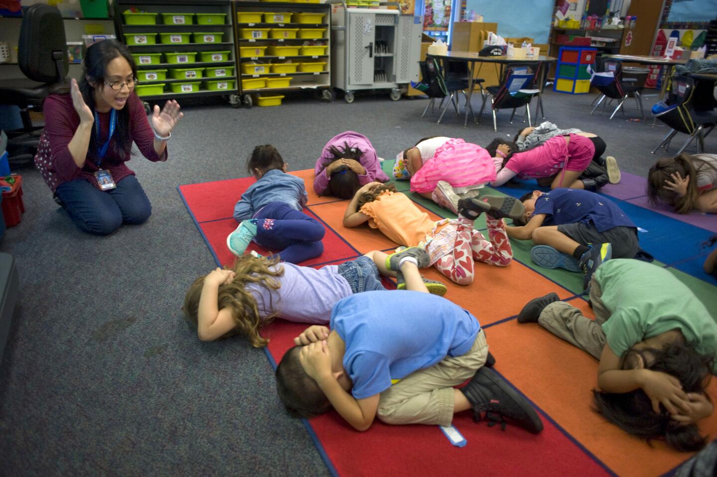 La maestra de preescolar, Cherrylyn Fidel, indica a sus alumnos cómo agacharse y cubrirse en un terremoto, durante el simulacro de sismo llamado "Great ShakeOut" (La Gran Sacudida) en la Escuela Primaria Hickman en San Diego, California.