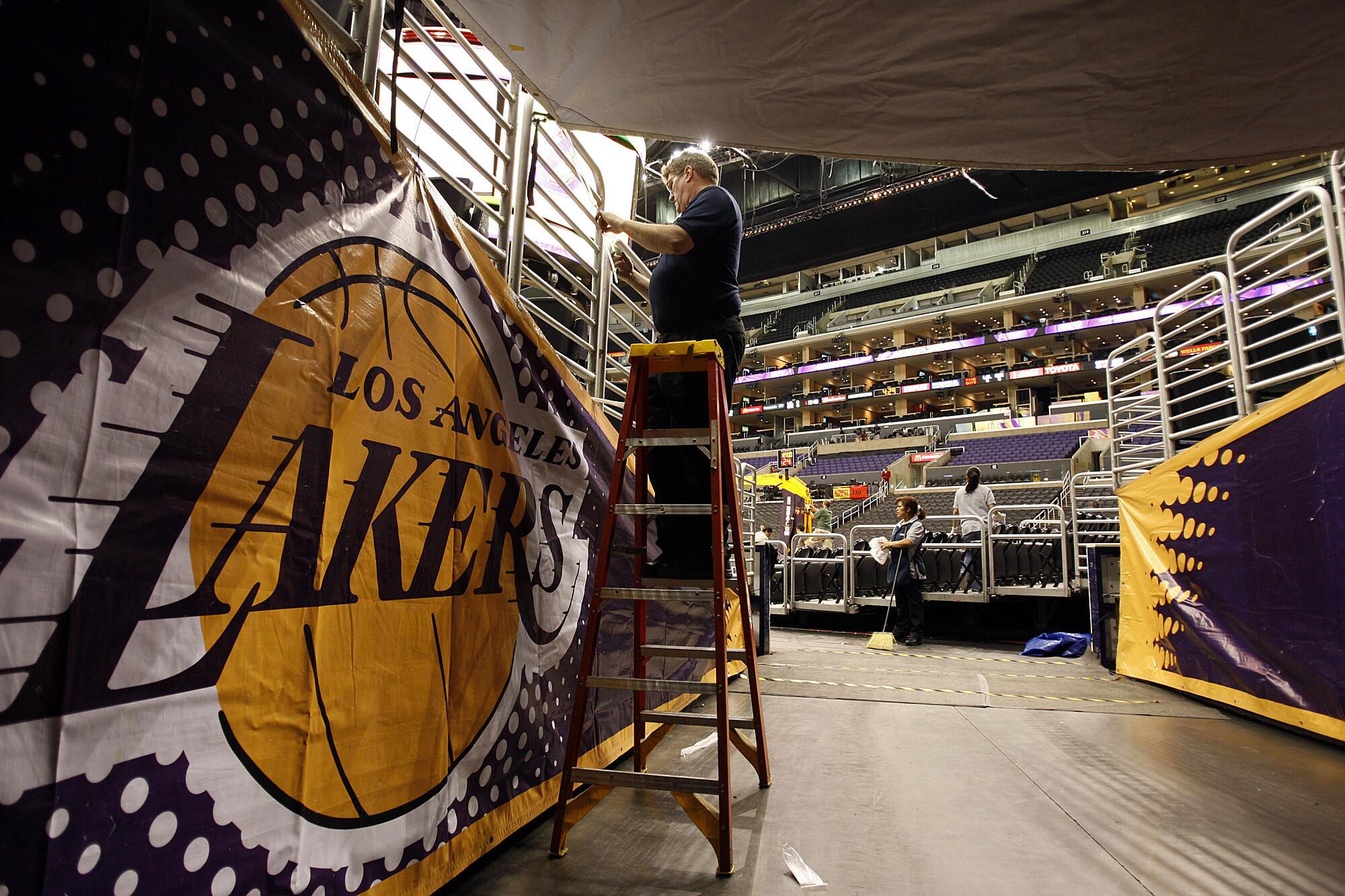 An arena worker puts up a Lakers banner in a tunnel as its converted from a Clippers game played earlier in the day.