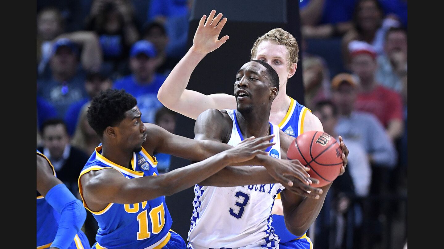 UCLA's Isaac Hamilton and Thomas Welsh, right, try to steal the ball from Kentucky's Edrice Adebayo during the first half of a Sweet 16 game on March 24.