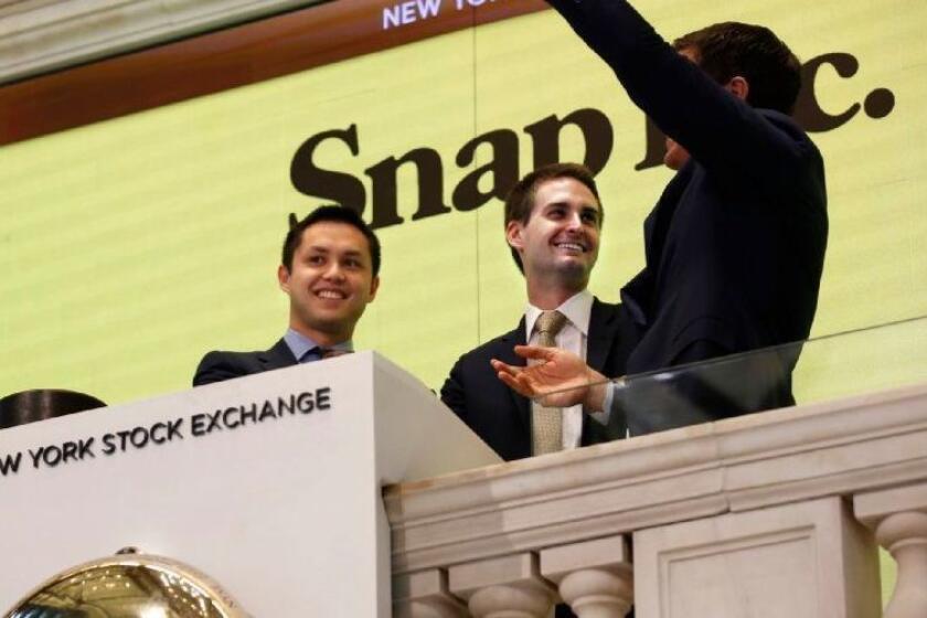 NEW YORK, NEW YORK--MARCH 2, 2017--Snap Inc. will make it's debut on the New York Stock Exchange on March 2, 2017. CEO Evan Spiegel, center, rings the bell at the NYSE for its debut, along with colleague Bobby Murphy, left, and NYSE President Thomas Farley, right. Snap Inc. is the parent company of Snapchat. (Carolyn Cole/Los Angeles Times)