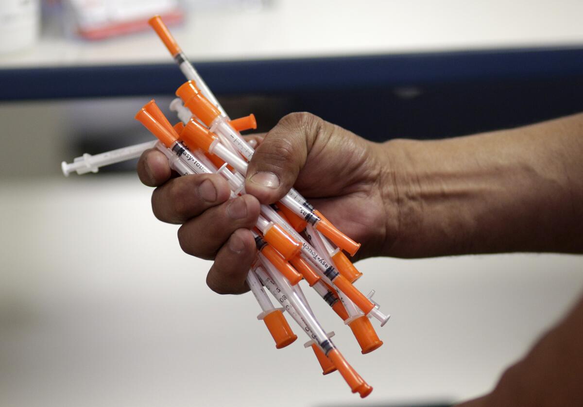 A photo of a hand gripping multiple syringes.