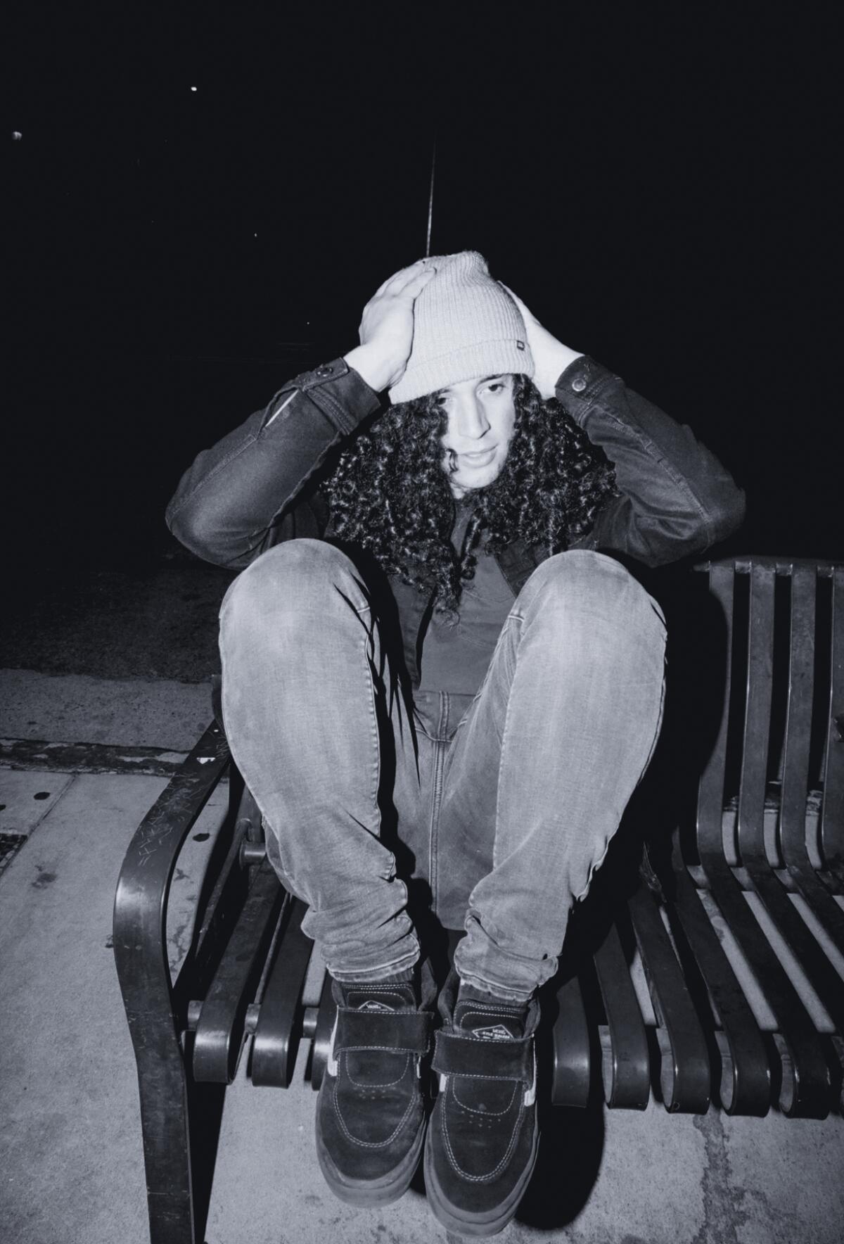 black and white photo of a woman in a beanie sitting on a bench 