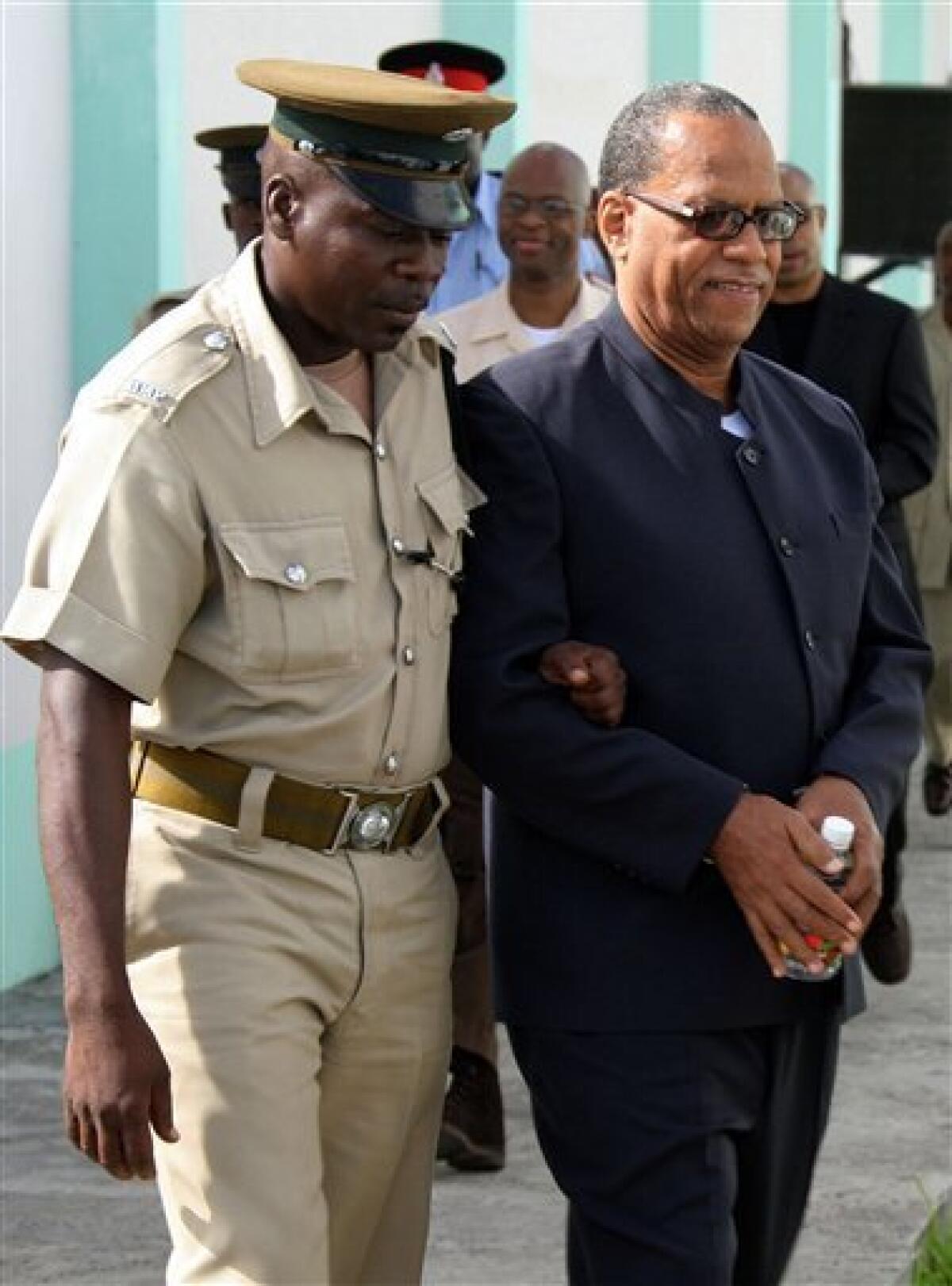 FILE - In this Monday, June 18, 2007 file photo, Grenada's former Deputy Prime Minister, Bernard Coard, right, is escorted by a prison guard upon his arrival to the Grenada Supreme Court for a re-sentencing hearing in St. George's, Grenada. Former Deputy Prime Minister Bernard Coard and six other men convicted of killing Grenada's leader in the 1983 coup that triggered a U.S. invasion strode out of prison on Saturday, Sept. 5, 2009, the last of 17 who had been sentenced for the crime. (AP Photo/Harold Quash, file)