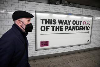 A man wearing a face mask walks past a health campaign poster in London