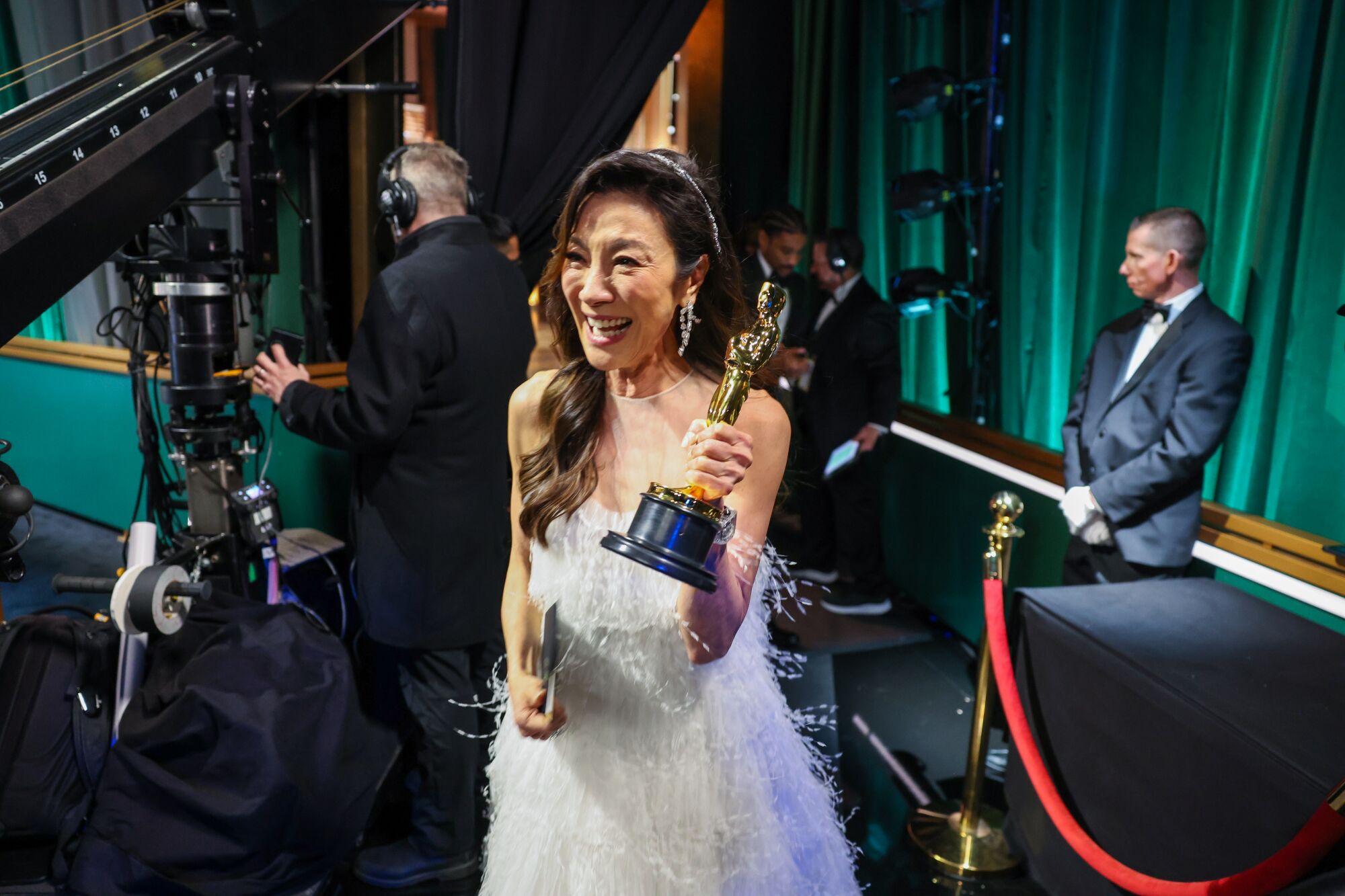 A woman in a white dress holds up an Oscar backstage at the 95th Academy Awards at the Dolby Theatre.