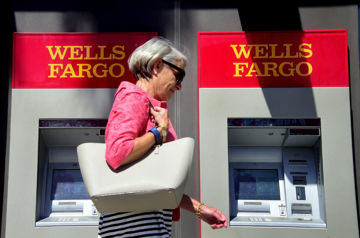 A woman walks past a Wells Fargo ATM in Pasadena in September.