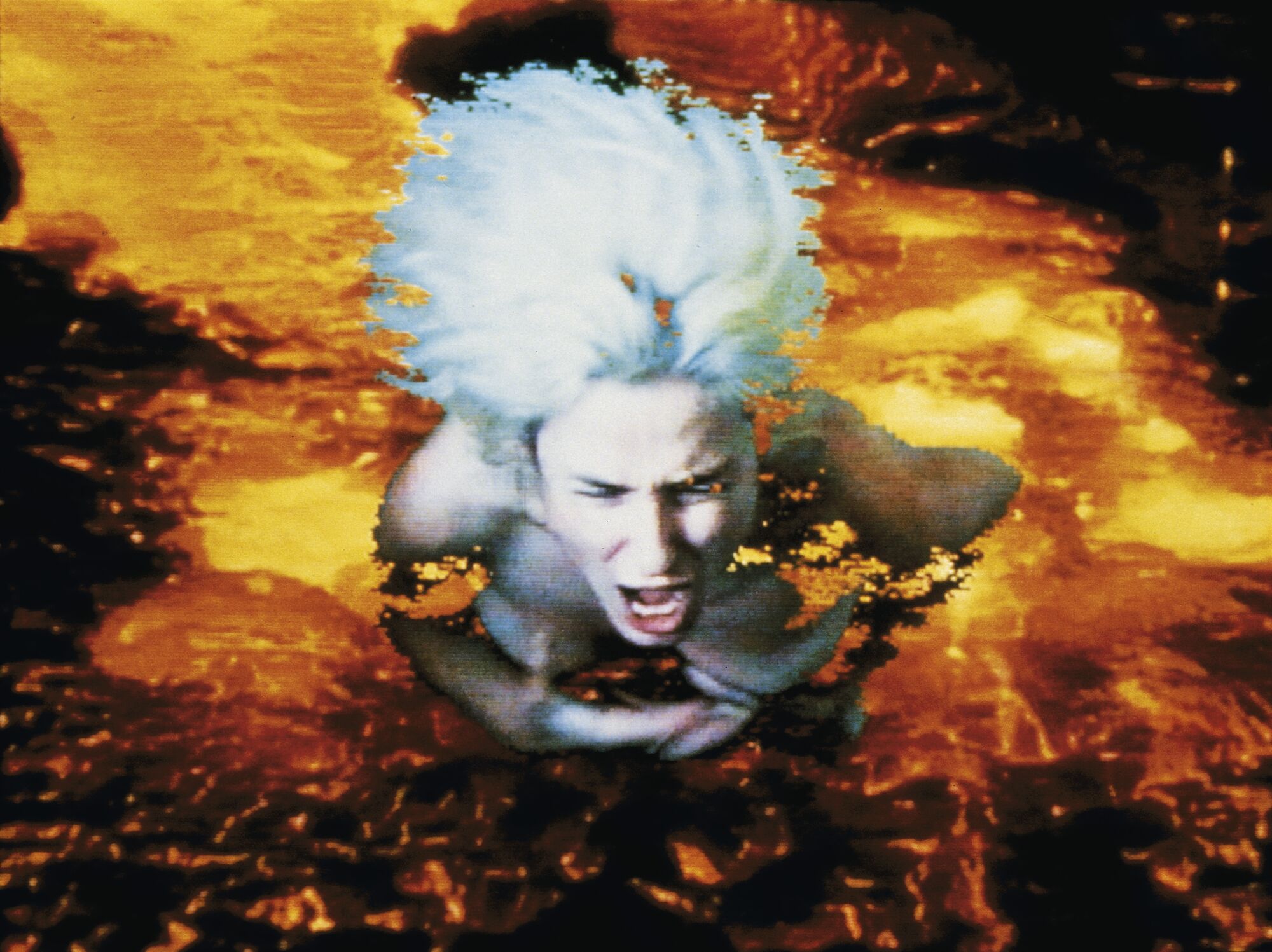 A video still shows a photo of a blonde woman screaming superimposed on a backdrop of lava