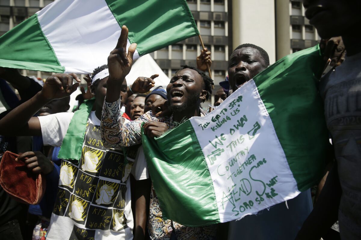 People hold green-and-white banners as they protest against police brutality in Lagos, Nigeria.