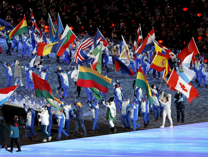 Performers carry flags during the closing ceremony of the 2022 Olympics.