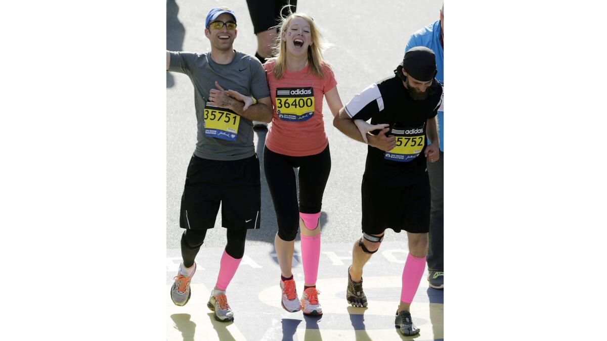 Timothy Haslet, left, and David Haslet celebrate with sister Adrianne Haslet-Davis as she crosses the finish line of the 118th Boston Marathon in April 2014. A year earlier, Adrianne Haslet-Davis, a professional dancer, lost her leg in the Boston Marathon bombing.