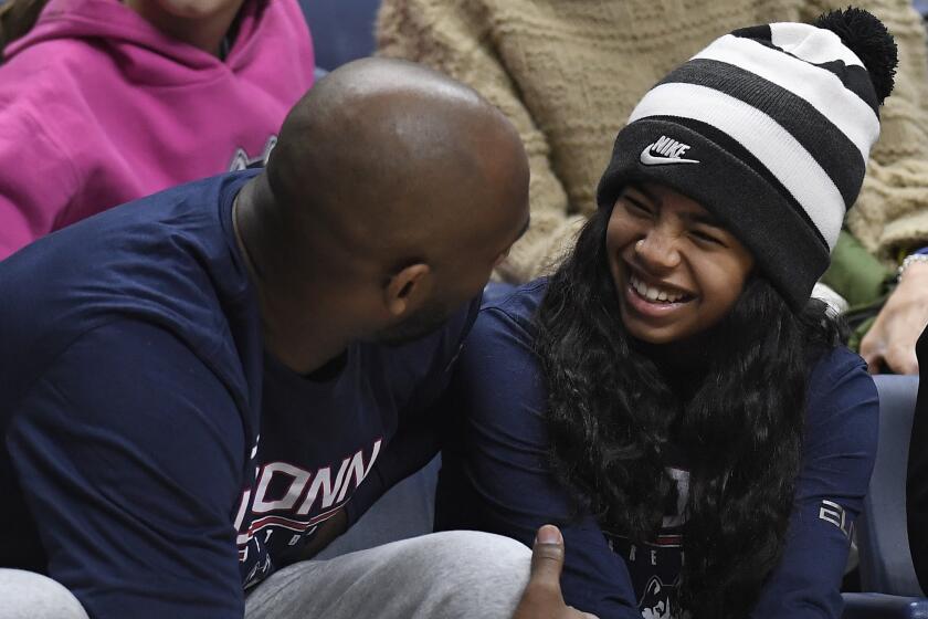 Kobe Bryant and his daughter Gianna watch the first half of an NCAA college basketball game between Connecticut and Houston.