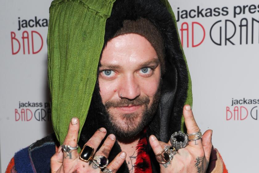 Bam Margera poses in layers of clothing and holds up his hands with many rings