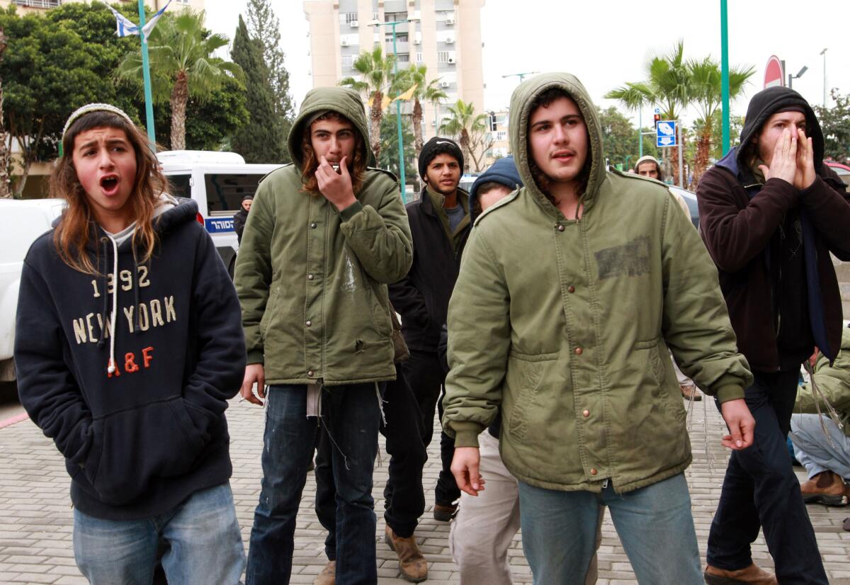 Israeli right-wing activists protest outside the courthouse in the central Israeli city of Lod, where two extremists were charged in a July arson attack.