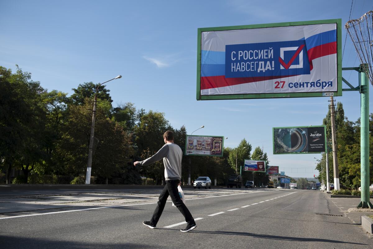 Un hombre cruza una calle junto a un letrero que dice: "Con Rusia para siempre,
