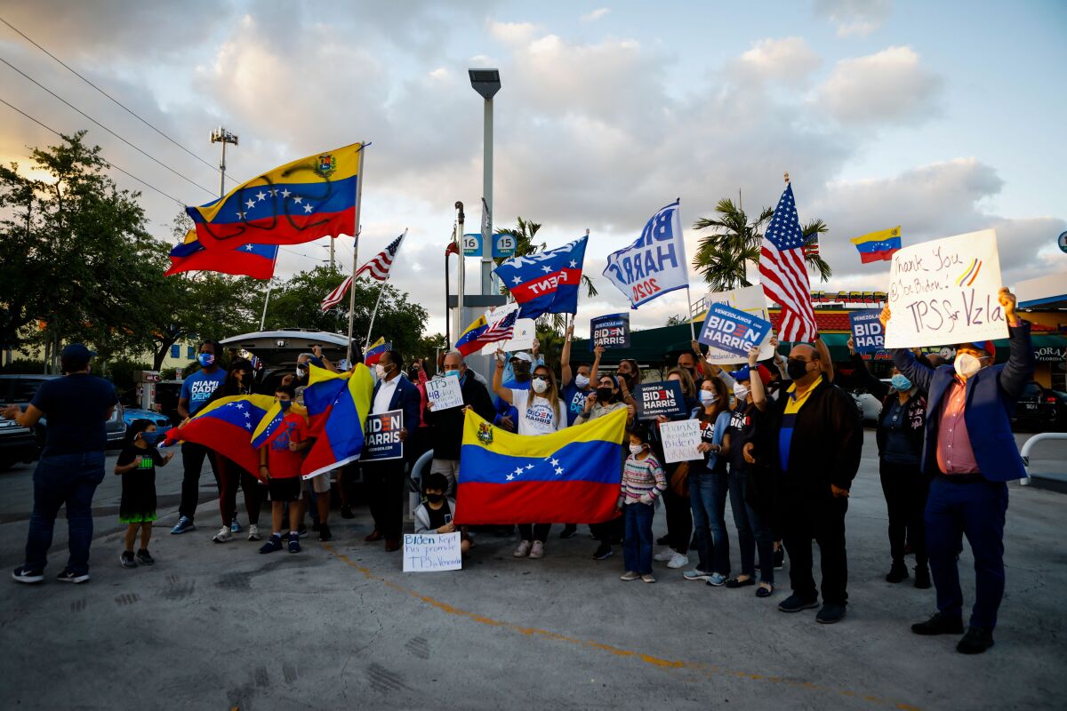 People celebrate, some holding Venezuelan flags, outdoors