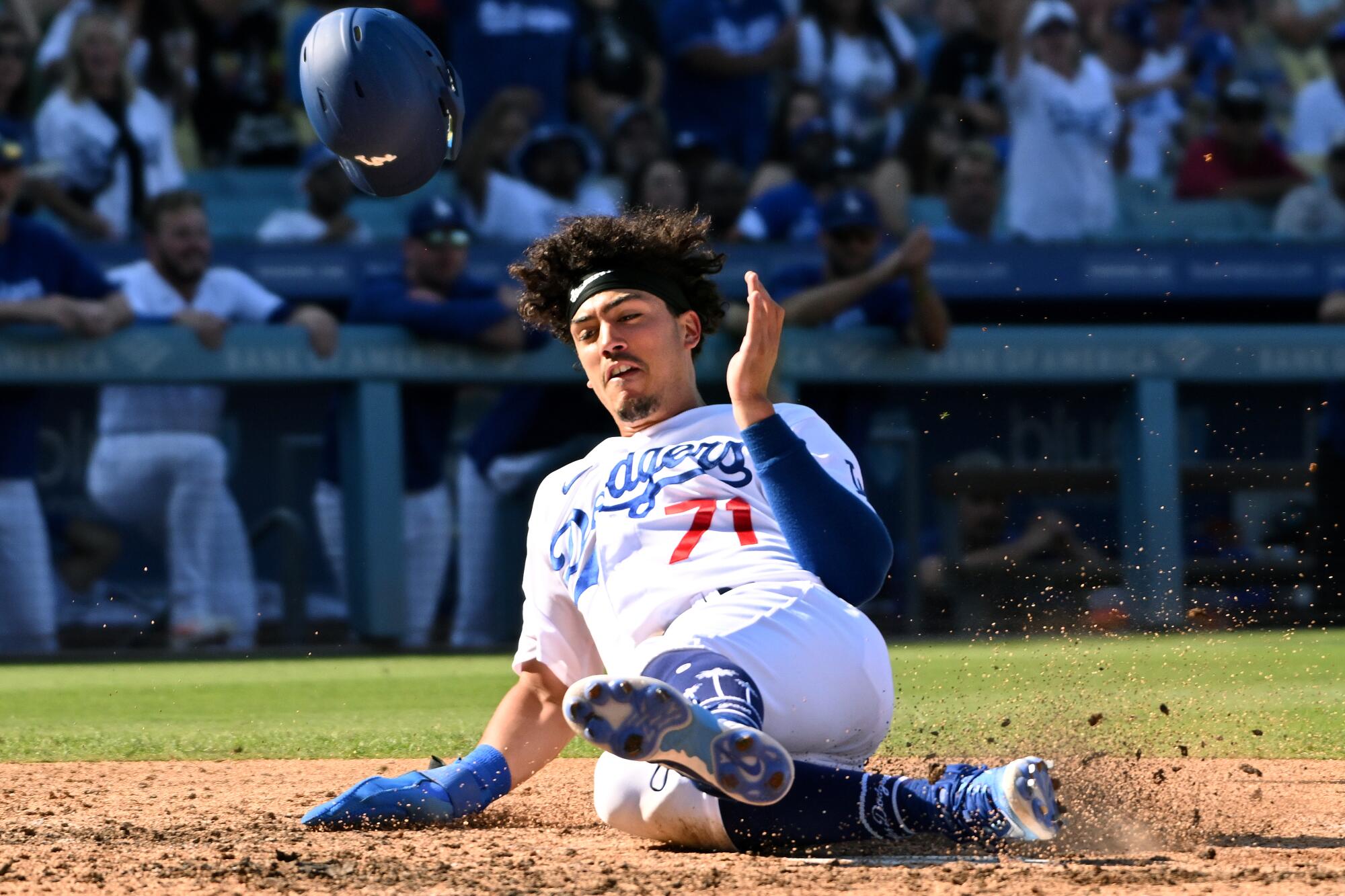 Dodgers rookie Miguel Vargas has his helmet fly off his head as he slides into home plate.