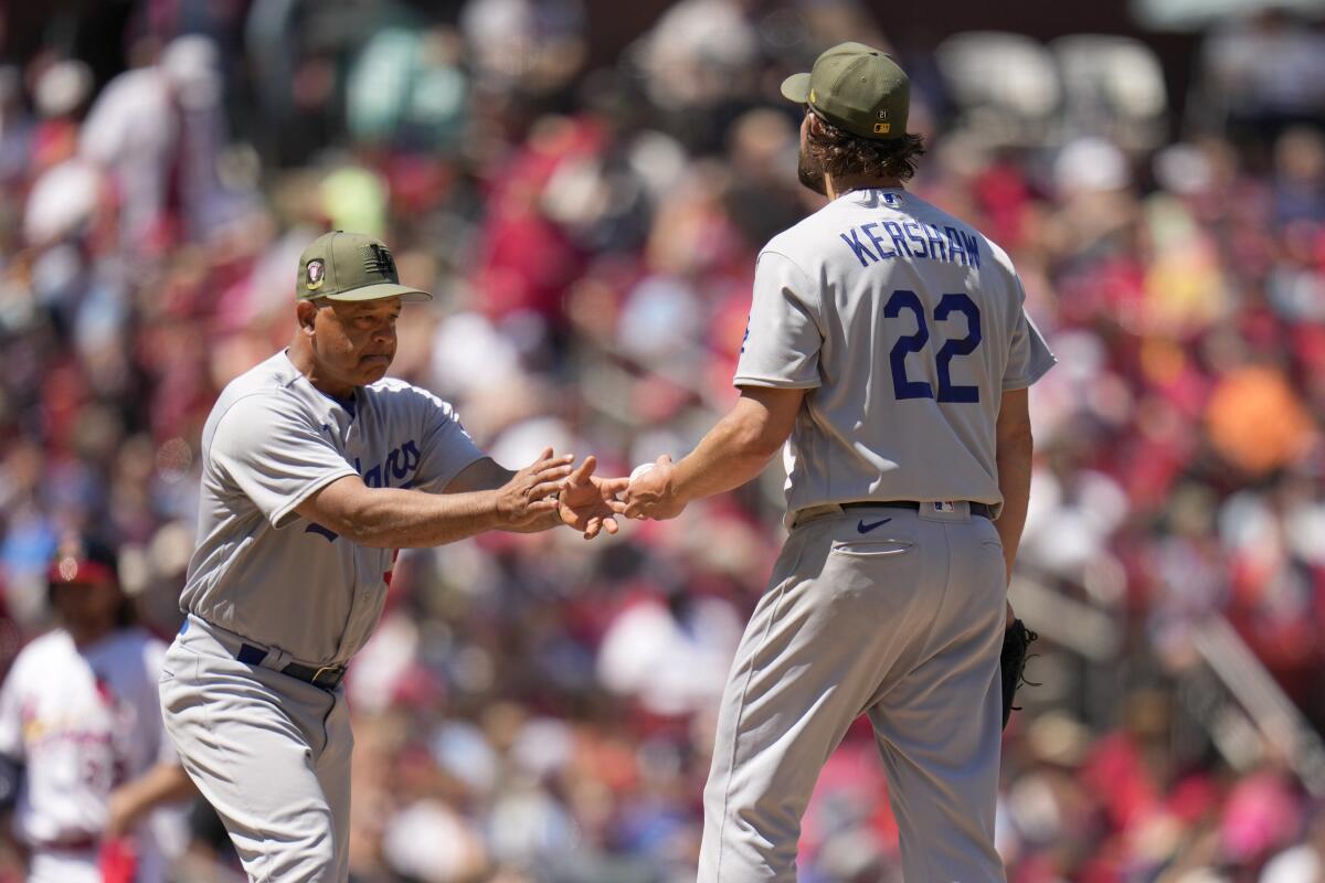 Dave Roberts reaches out for Clayton Kershaw's hands.