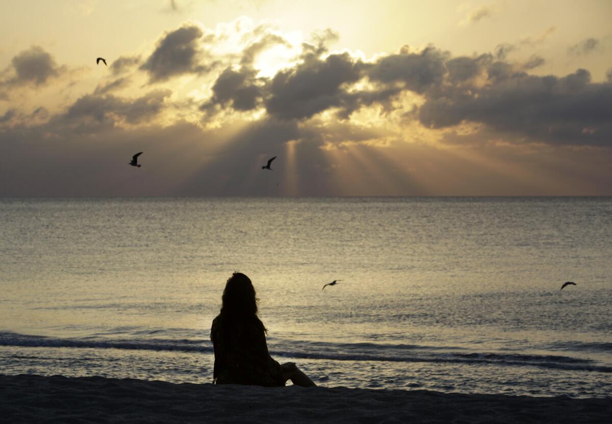 A woman meditates on the beach. 