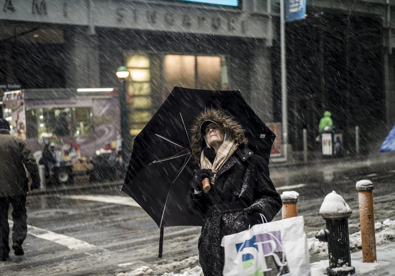 A woman looks up at the skyline and falling snow in New York City.