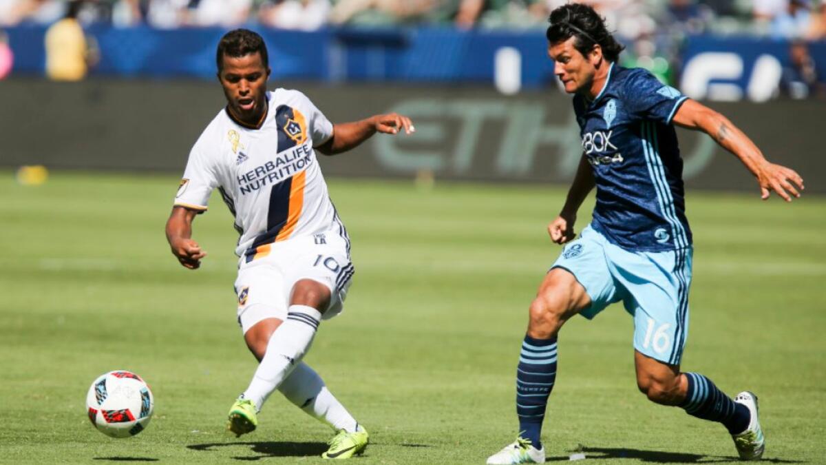 Galaxy midfielder Giovani dos Santos, left, moves the ball away from Seattle forward Nelson Valdez during a game on Sept. 25.