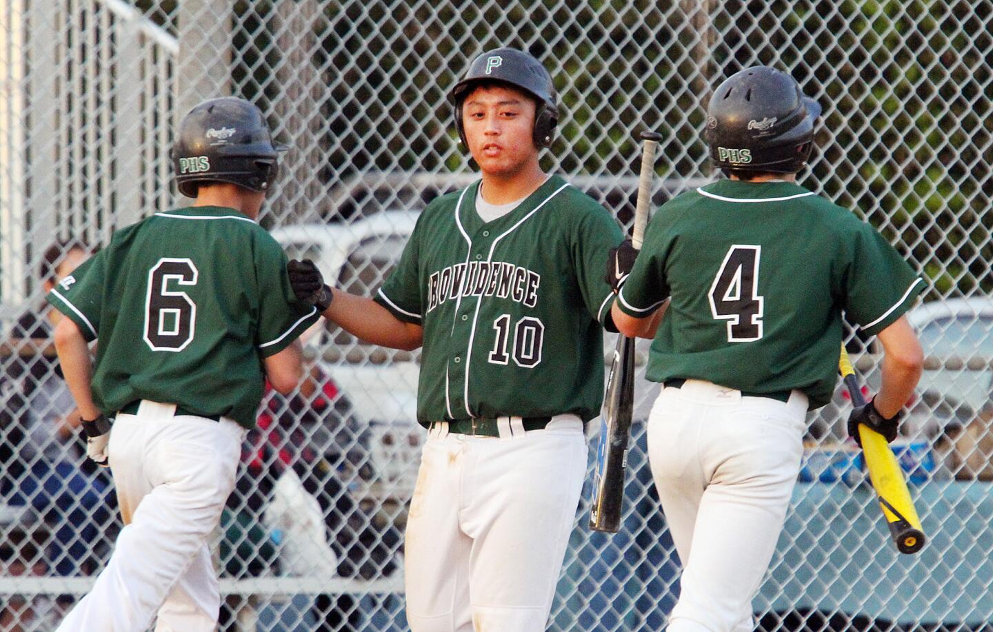 Providence's Mason Inumerable (10) fist bumps teammates Ryan Chow (6) and Thomas Keller (4) after they scored against Torah in a non-league baseball game at Ralph Foy Park in Burbank on Tuesday, March 11, 2014.