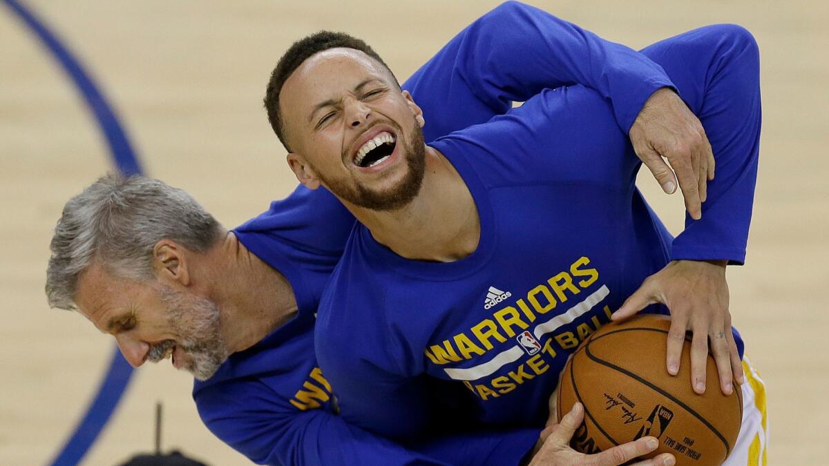 Warriors guard Stephen Curry, right, and assistant coach Bruce Fraser have some fun during warmups before Game 5 of the NBA Finals last season.