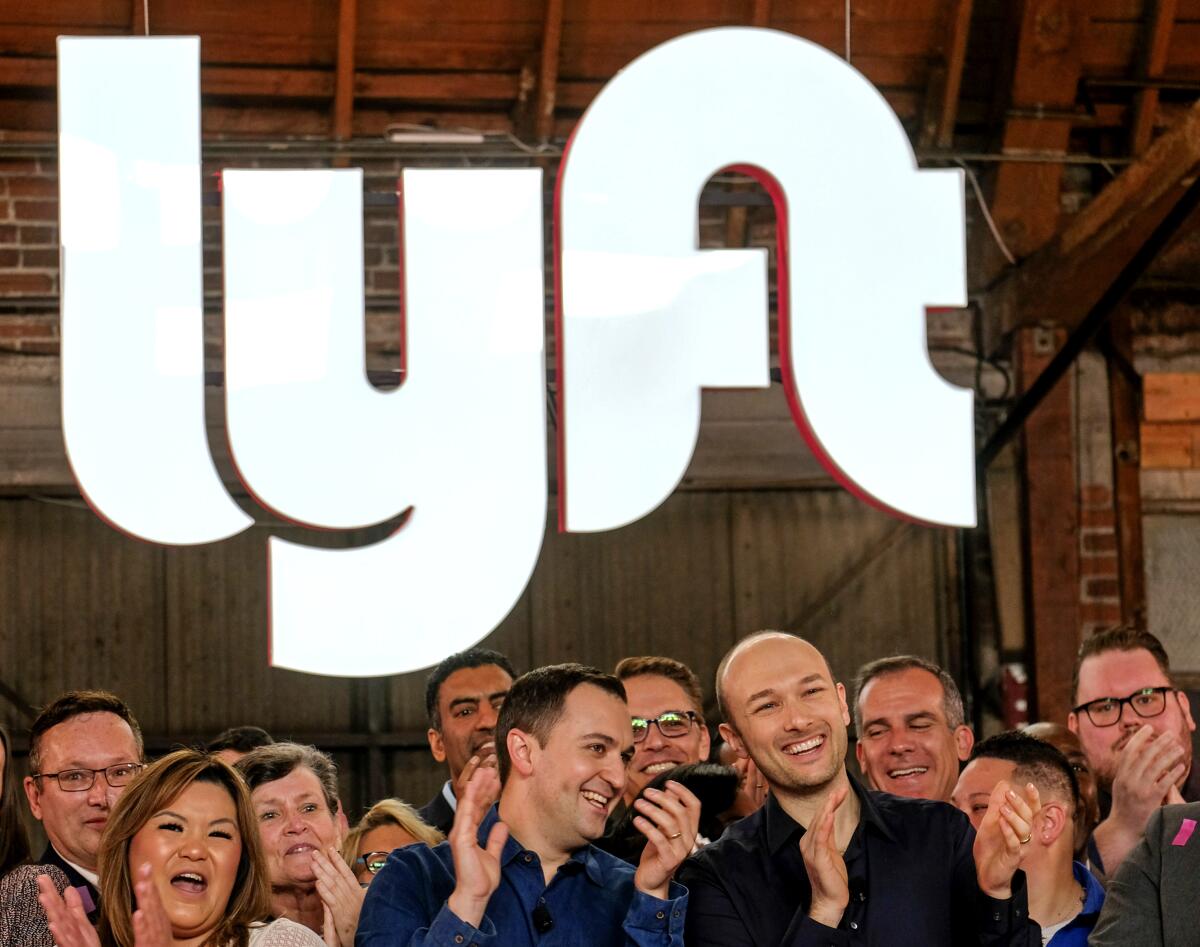 A group of people applaud under a Lyft logo.