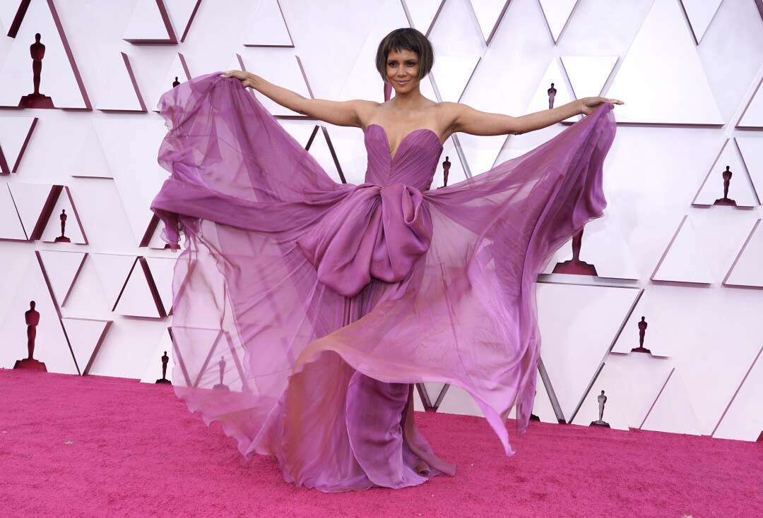 Halle Berry holding out the flowy skirt of her strapless light purple gown