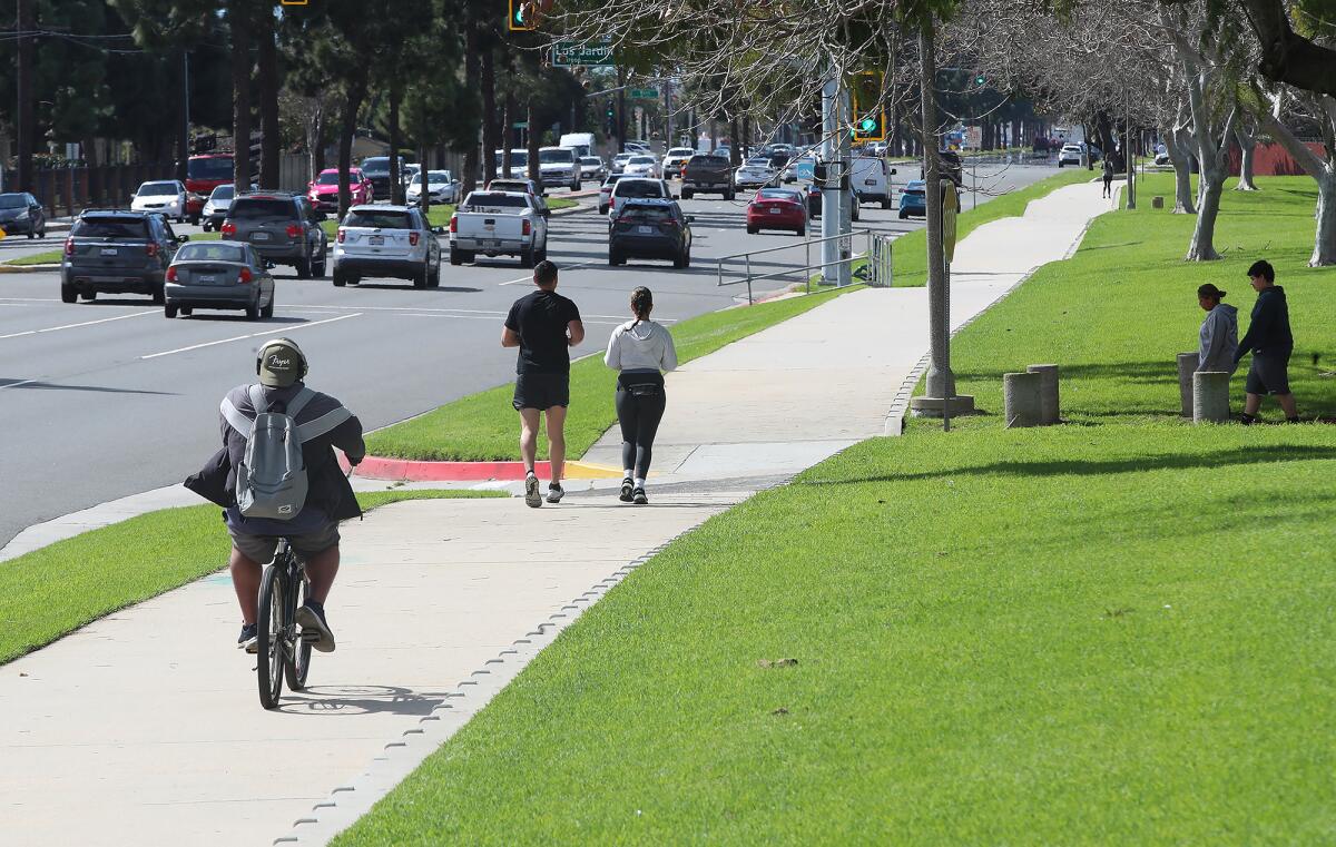 Visitors of Mile Square Park exercise alongside a busy city street on Tuesday in Fountain Valley.