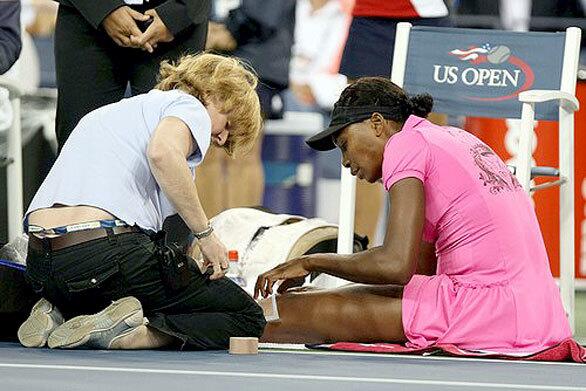 A trainer works on the leg of Venus Williams during her first-round match Monday.