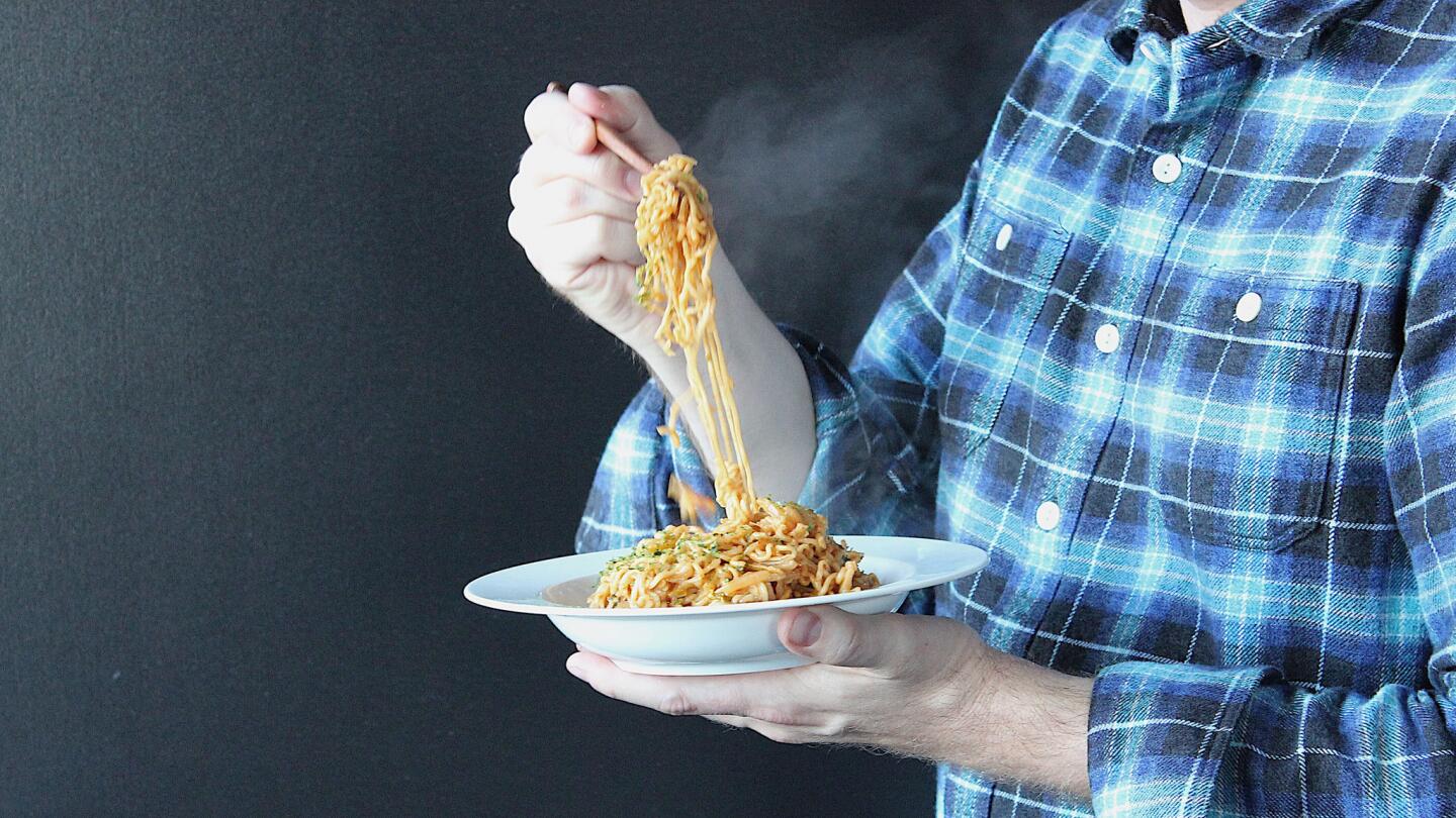 Chicago Tribune Food and Dining reporter Nick Kindelsperger lifting his instant ramen Sapporo Ichiban chow mein noodles with butter, kimchi and American cheese.