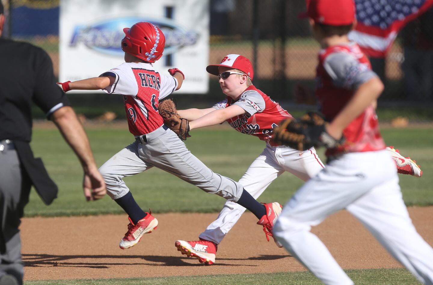Newport Beach shortstop Charlie Kaster tags a Dana Point base runner stuck in a rundown during PONY Mustang 10-and-under section tournament at Del Obispo Community Park in Dana Point on Thursday.