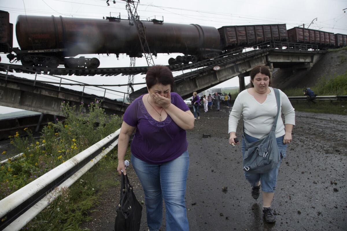 Distraught civilians in eastern Ukraine pass beneath a railroad bridge blown up July 7 over the main highway between Donetsk and Slovyansk.
