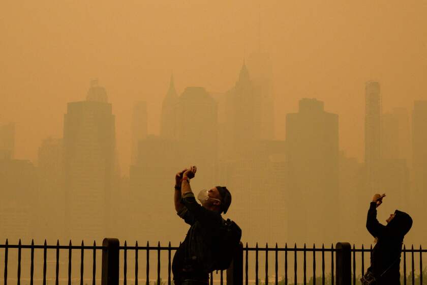 People take photos of the sun as smoke from the wildfires in Canada cause hazy conditions in New York City on June 7, 2023. Smoke from Canada's wildfires has engulfed the Northeast and Mid-Atlantic regions of the US, raising concerns over the harms of persistent poor air quality. (Photo by ANGELA WEISS / AFP) (Photo by ANGELA WEISS/AFP via Getty Images)