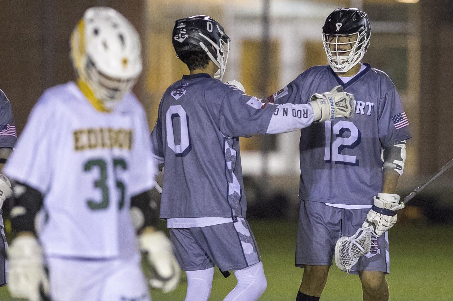 Newport Harbor's Hunter Rouch (0) high fives Zach Quinonez (12) afgter he scored a goal during a Sunset League game against Edison on Wednesday, March 28.