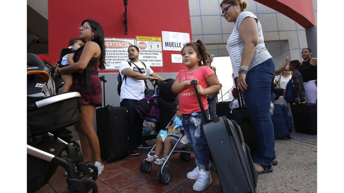 Cesar Ayala, second from left, and his family, including wife, Indira Viera, 38, right, daughters Sarah, center, and Lilly, in stroller, board an evacuation cruise ship.