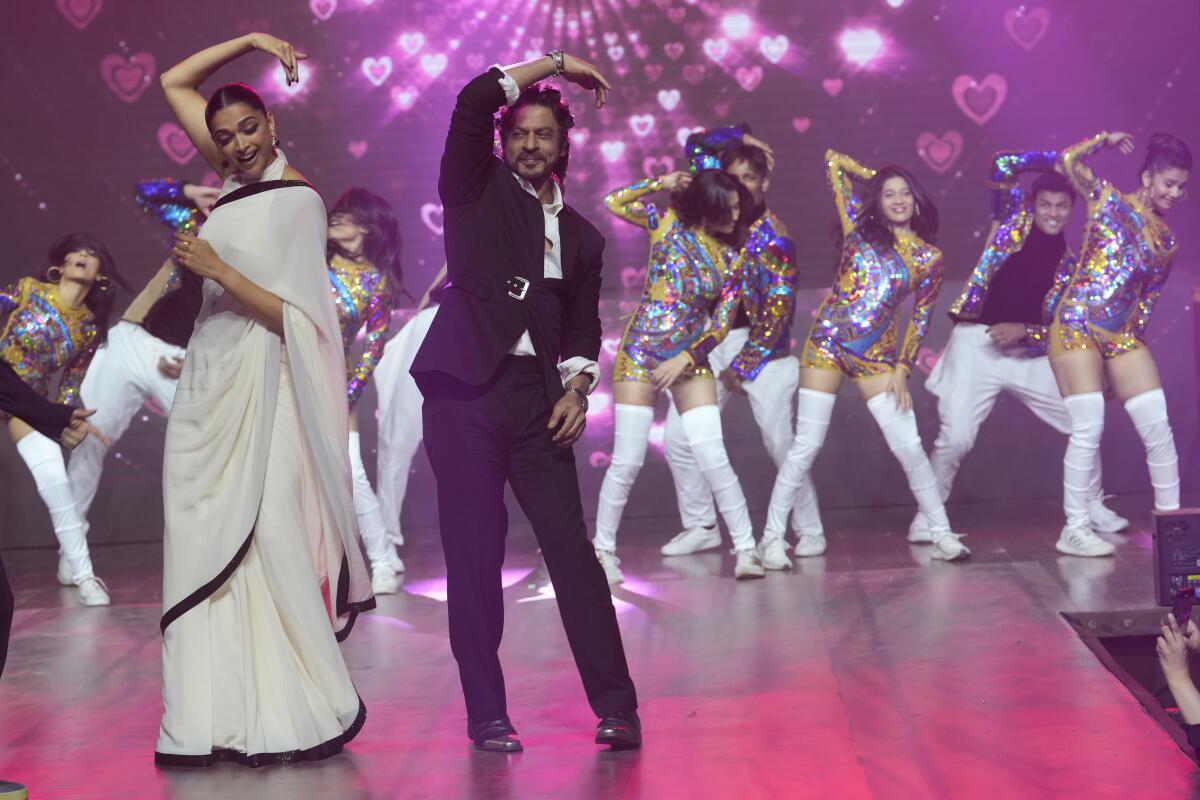 Deepika Padukone dances with Shah Rukh Khan as other Bollywood actors dance in the background.