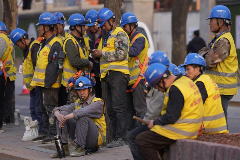 Trabajadores esperan transporte afuera de una obra, el martes 9 de abril de 2024, en Beijing.(AP Foto/Ng Han Guan)