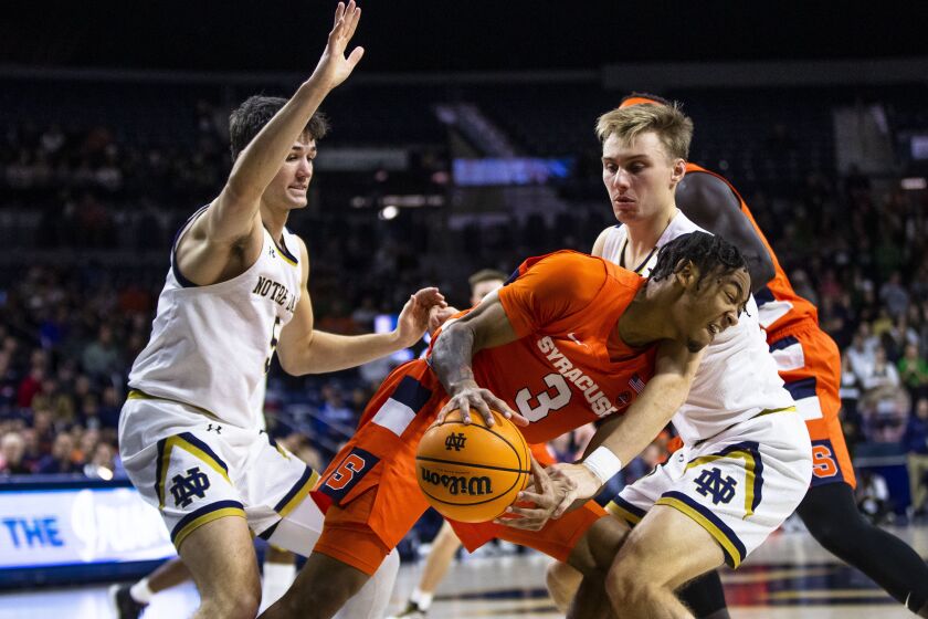 Syracuse's Judah Mintz (3) tries to get around as Notre Dame's Dane Goodwin, right, and Cormac Ryan, left, defend during the first half of an NCAA college basketball game on Saturday, Dec. 3, 2022 in South Bend, Ind. (AP Photo/Michael Caterina)